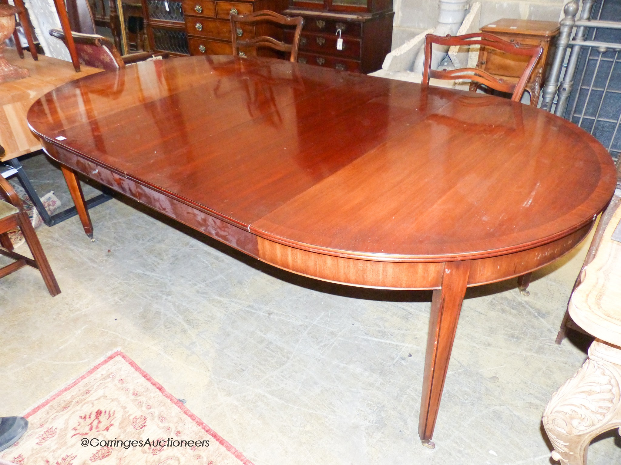 A reproduction George III Style mahogany D-end extending dining table, 236cm extended, 2 spare leaves. W-130, H-74cm. Together with six ladder back dining chairs, two with arms.